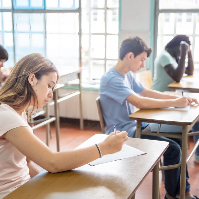 Group of multi ethnic high school students having test at classroom